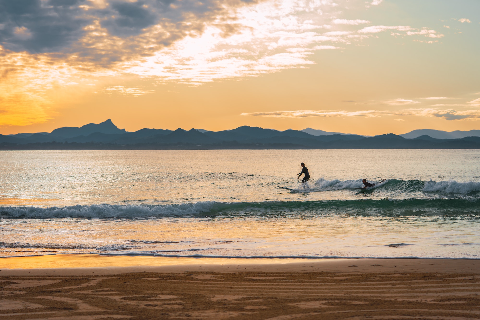 people doing surf in Byron bay, Australia at sunset